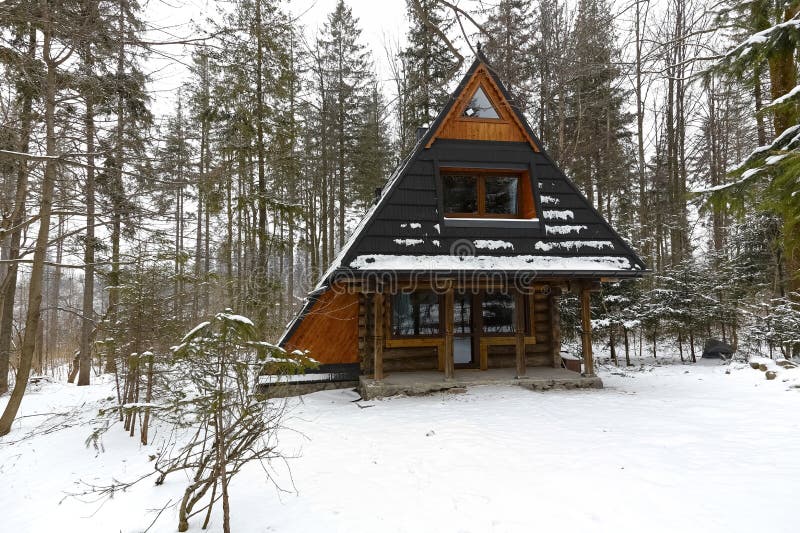Small wooden building by the forest. Zakopane, Poland - March 20, 2018: A small wooden building with a steep and sloping roof is seen in the winter scenery at royalty free stock image